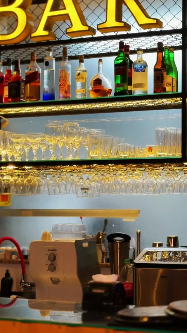 Prateleiras do bar com garrafas e taças sob o letreiro Bar
