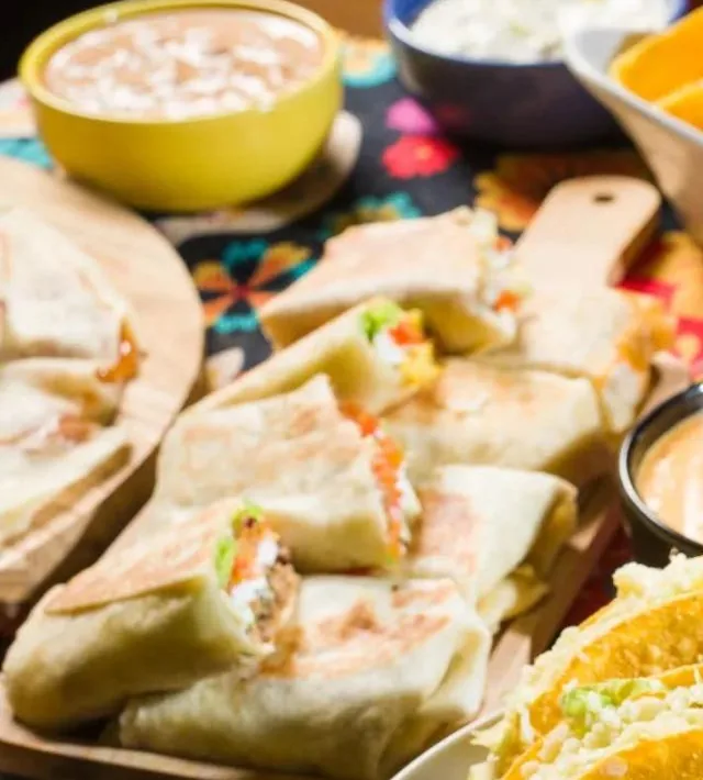Burritos cortados ao meio numa tábua, com recheio à mostra