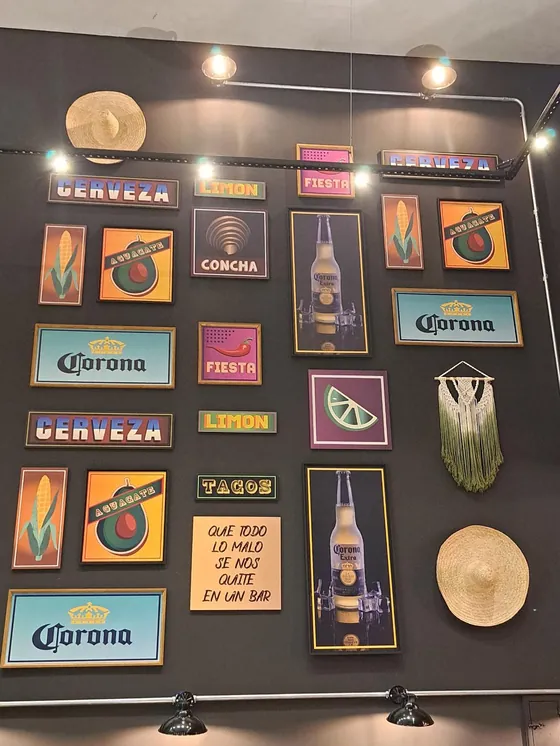 Parede com quadros de cerveja, limão, tacos e fiesta, e um sombrero de palha